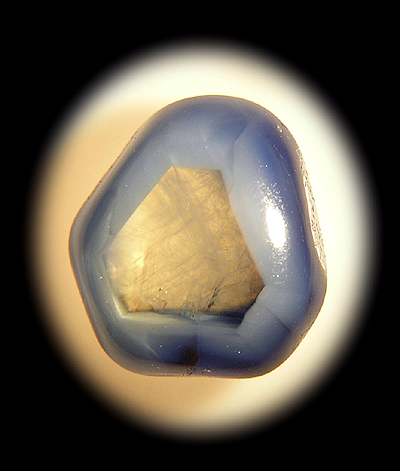 Polished sapphire pebble with colorless transparent center, showing its trigonal symmetry.